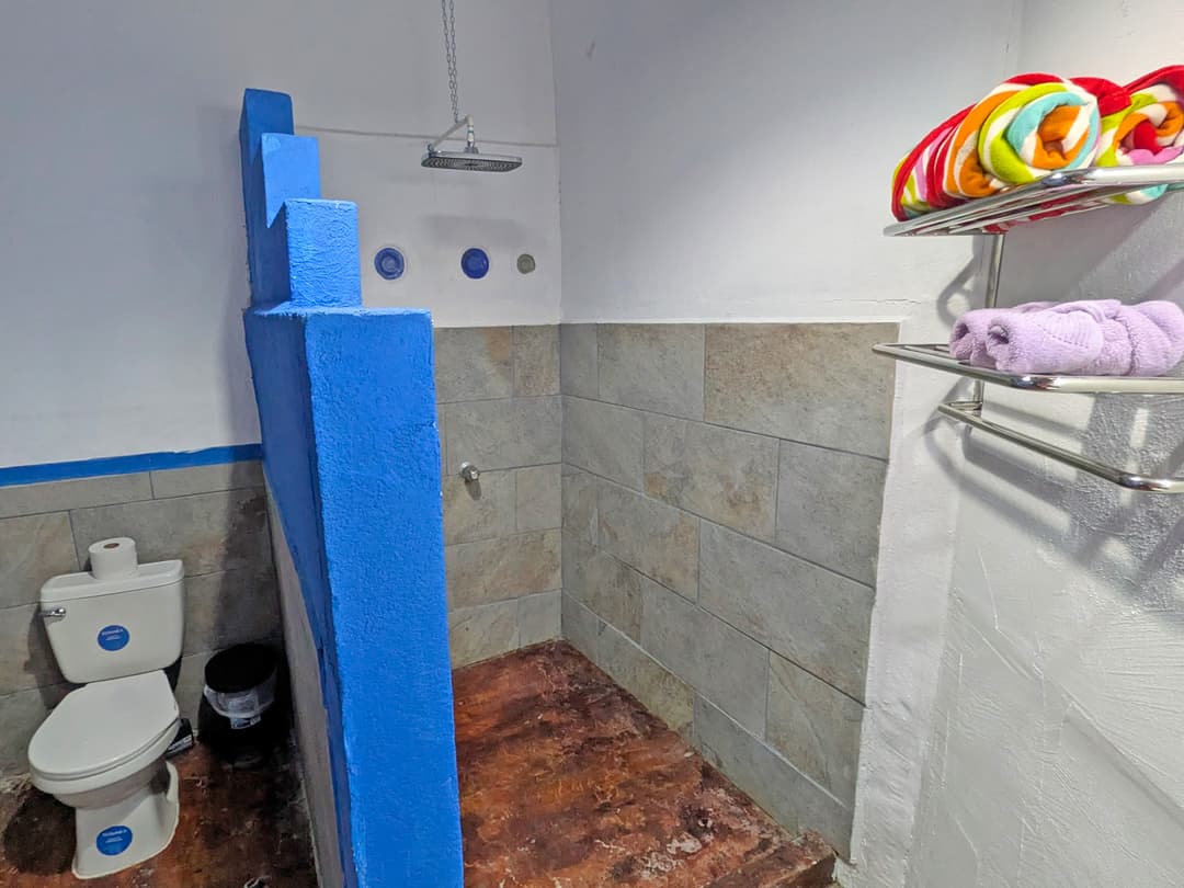 Full bathroom with warm shower, tiled floor and natural light from a louvered window